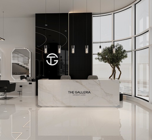 Reception at The Galleria Hair Beauty Lounge in Dubai Media City: white marble desk, black feature wall with the TG monogram, and curved floor-to-ceiling windows